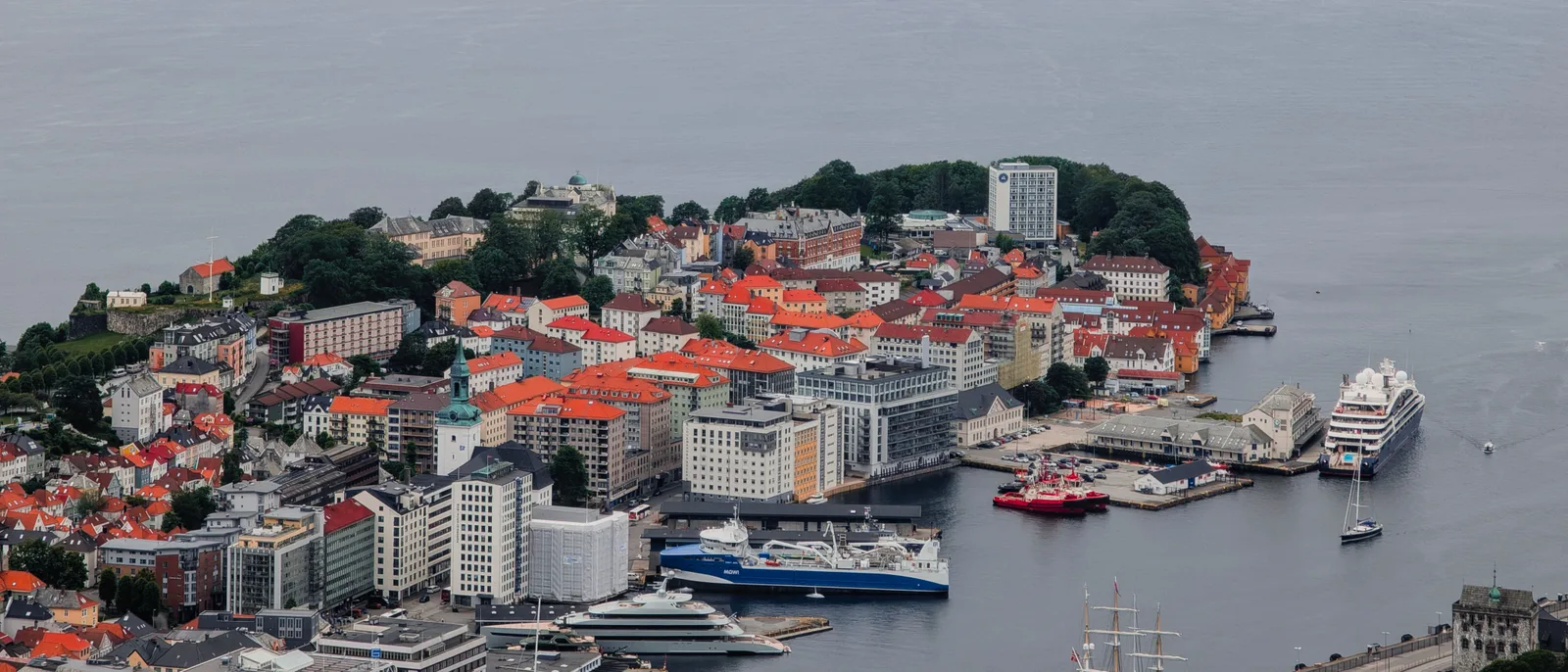 Bergen seen from the air, the Vågen inlet and the old town peninsula, a cargo quay and a ship berthed on the far side.
