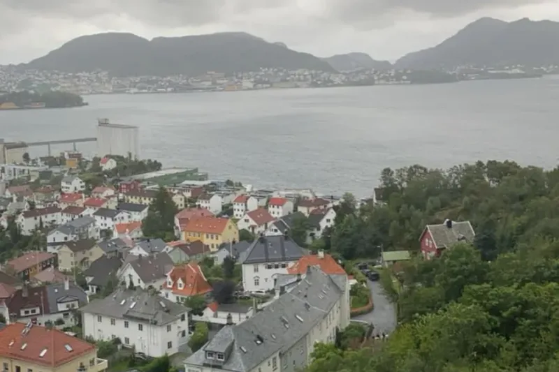 Wet Bergen rooftops seen from the Fløibanen funicular in the rain, the harbour grey beyond the tiled roofs.