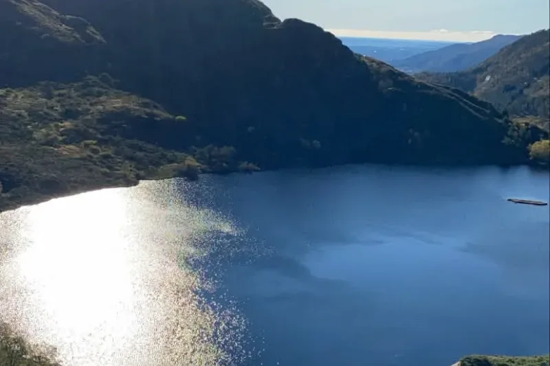 A mountain reservoir in the hills above Bergen in autumn, still water ringed by faded grass and low cloud.